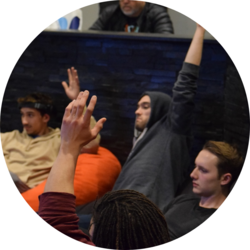 Several students raise their hand to answer a question asked during residence hall worship.